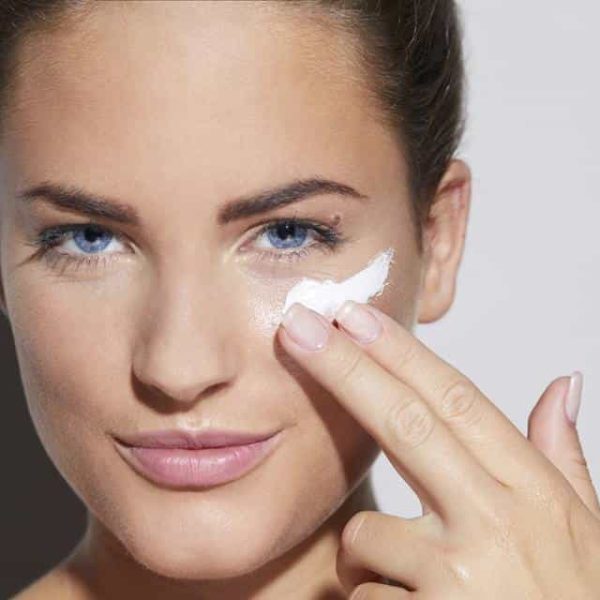 Portrait of beautiful young woman applying skin cream